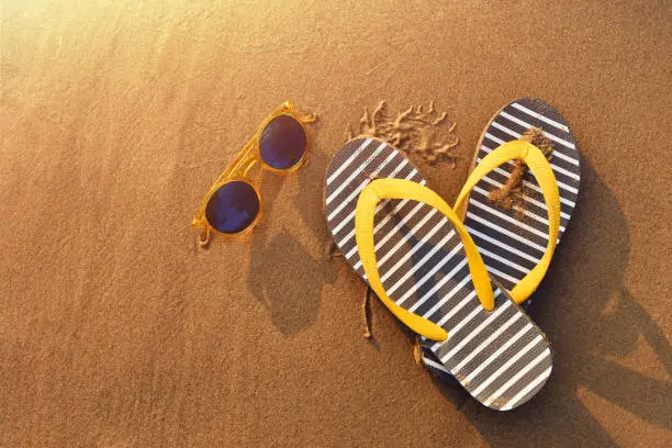 Sandal and sunglasses on beach, Warm tone with golden summer sunset light, Top view