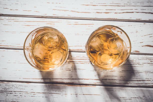 istock Whiskey glasses with ice cubes on white wooden table 687187100