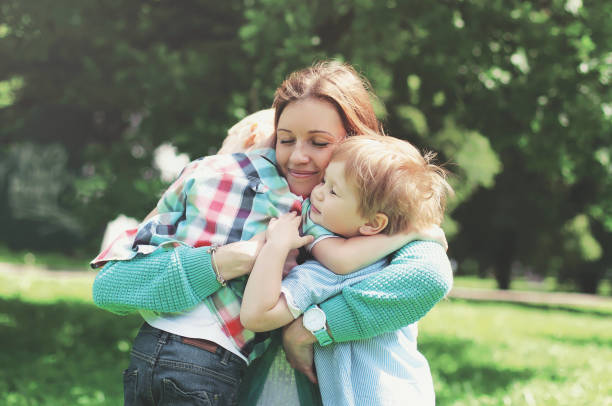 Happy smiling mother is embracing children at summer day stock photo
