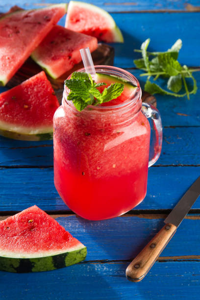 istock Tasty fresh appetizing watermelon drink smoothie with mint on blue table. Closeup. 687213058