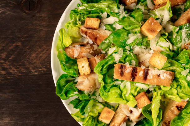 istock Closeup of plate of chicken Caesar salad on rustic texture 687214598