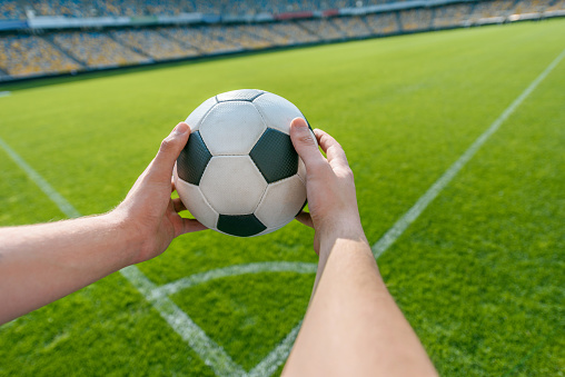 person holding soccer ball on soccer field stadium