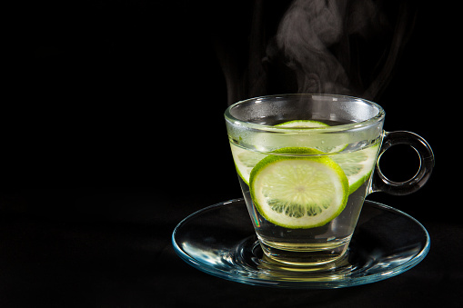 Steaming hot lemon water isolated on black background
