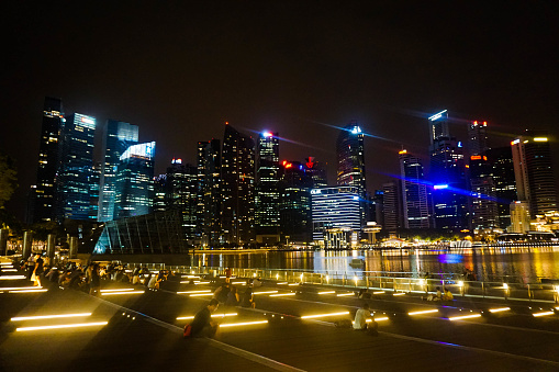 Singapore city downtown skyscrapers are pictured across the Marina Bay by night. Neon lights dominate the picture and are reflected in the water - Singapore 26/08/2016