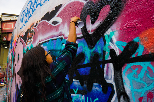 A Young Woman Grafittis a Black Heart onto a Wall at Leake Street Grafitti Tunnel London 17/08/2015