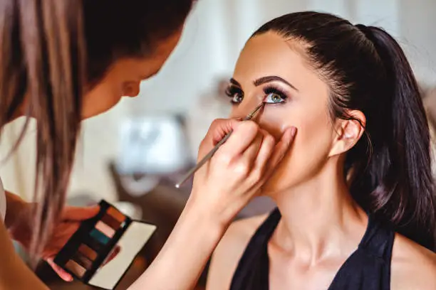 Photo of Makeup artist applying eyeshadow on a girl
