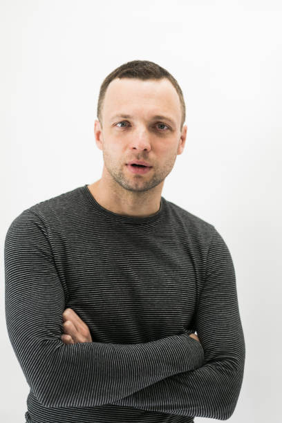 Close-up vertical studio portrait of young adult European man over white wall