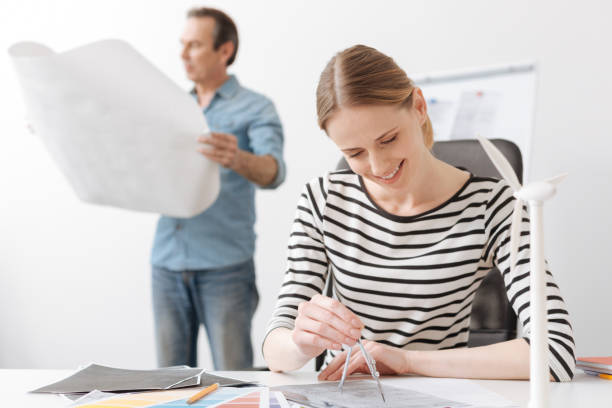 istock Positive professional woman engineer drawing with compasses 687253756