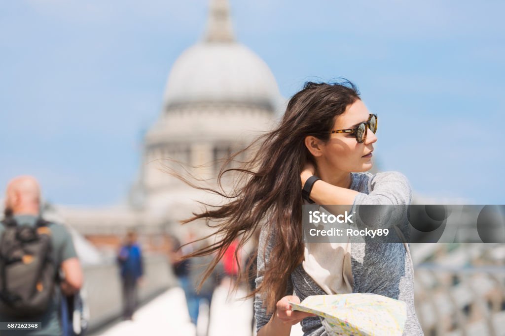 Travel-Blogger in London on Millennium Bridge, UK Beautiful travel blogger in London on Millennium Bridge, UK, looking at her map with St. Paul's Cathedral in the back Adult Stock Photo