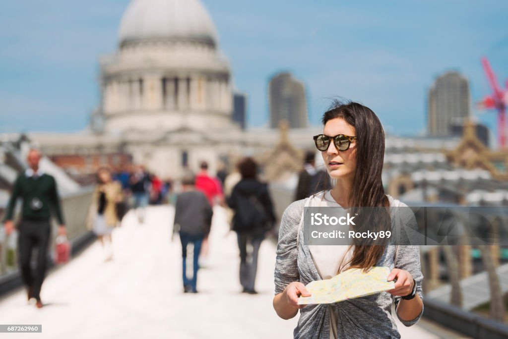 Travel-Blogger in London on Millennium Bridge, UK Beautiful travel blogger in London on Millennium Bridge, UK, looking at her map with St. Paul's Cathedral in the back London - England Stock Photo