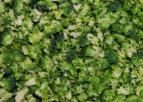 A heap of broccoli sliced and cut into small pieces, ready to be cooked or used in a salad. A pattern usable for backgrounds and such. As broccoli is healthy those vegetables stand for balanced and healthy nutrition.