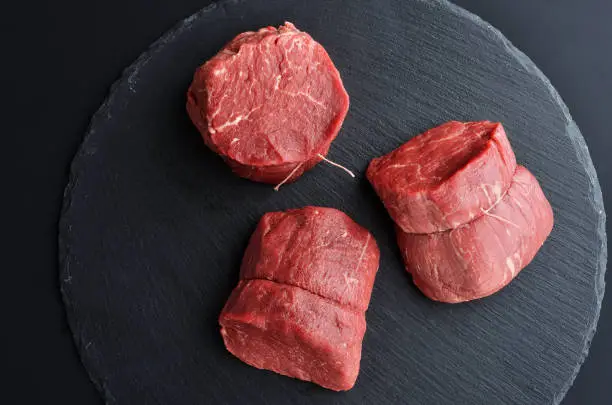 Photo of Three fresh raw Prime Black Angus beef steaks on stone background