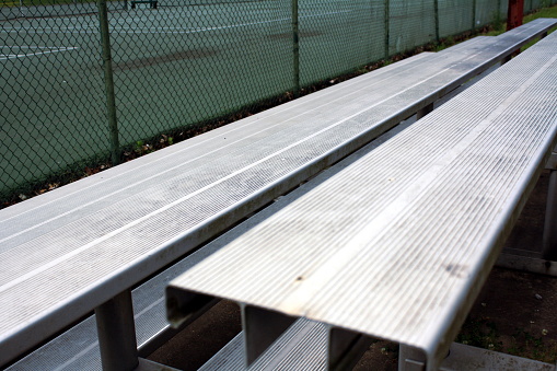 Metal bleachers at a hardcourt tennis court.