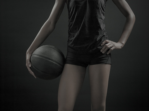 A desaturated image of an African Amercian women with a basketball on a black background.