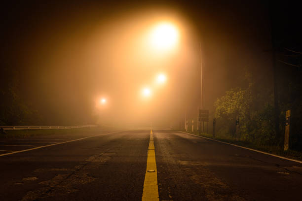 Country road with night light among the mist. stock photo