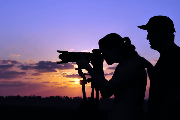 A photographer is teaching a student wildlife or landscape photography outdoors.