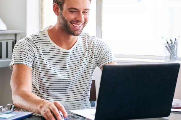 istock Happy young male student smiling while seated behind his laptop 687340946