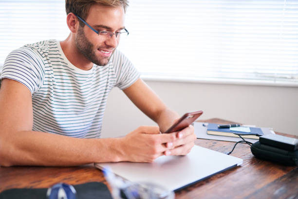 istock Attractive male student busy messaging on his cellphone at desk 687341154