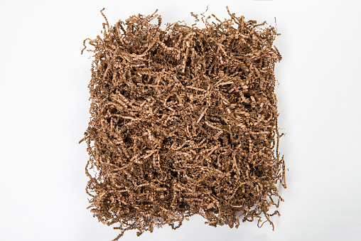 Close up of brown shredded corrugated paper packing material. White copy space surrounds image.