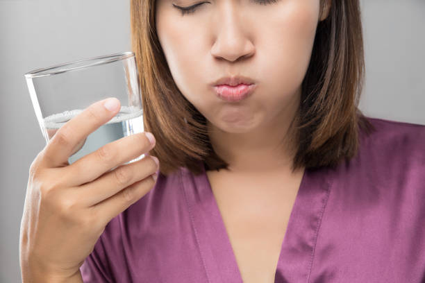 frau, spülen und gurgeln mit mundwasser aus einem glas während der täglichen mundhygiene routine, mädchen in lila seide gewand, dental healthcare konzepte - during stock-fotos und bilder