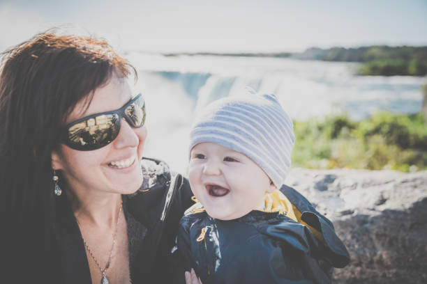 Mother and Baby Boy at Niagara Falls, they are smiling and having fun. The waterfalls are in the background