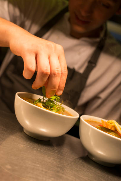 istock Chef Garnishing Bowl of Soup with Herbs 687359602