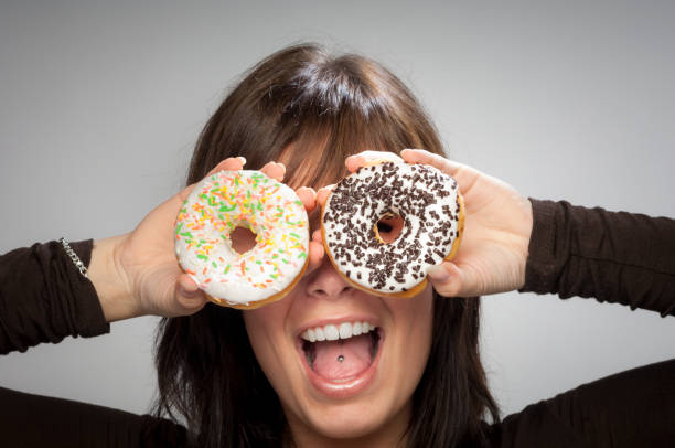 istock Donuts fun; Attractive Young Woman with Two Iced Donuts 687383300