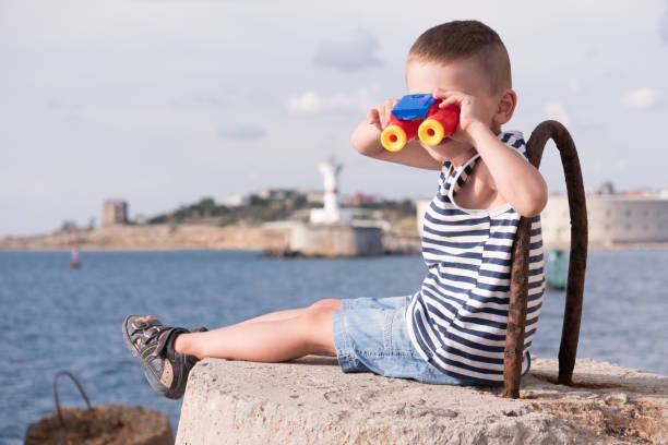 istock curious little boy looking into the distance through binoculars 687389066