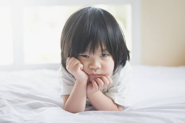 istock unhappy asian baby lying on white bed 687399448