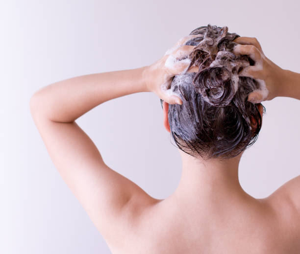 istock Woman shampoos hair close up with both hands on a white background 687401864