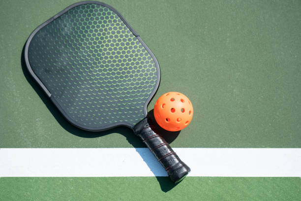 Pickle Ball Pickle ball and paddle on court pickleball stock pictures, royalty-free photos & images