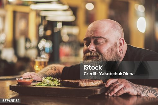 istock Obese male savoring grilled meat in pub 687425182