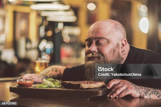 Obese Male Savoring Grilled Meat In Pub Stock Photo - Download Image Now - Eating, Food, Men