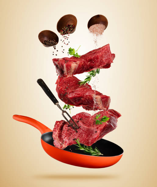 istock Flying raw steaks with cooking ingredients from pan 687425844