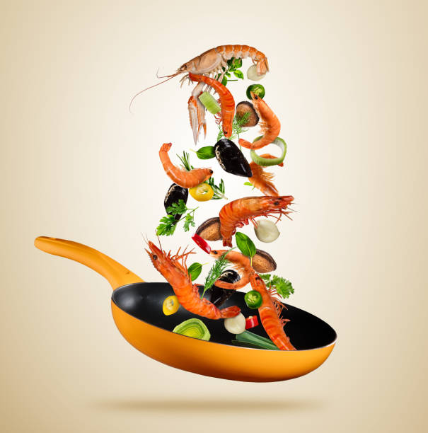 fresh sea food and vegetables flying into a pan on brown background - shrimp pan cooking prepared shrimp imagens e fotografias de stock