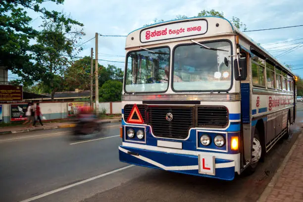 Photo of A blue and white bus parked by the side of the road in Anuradhapura, Sri Lanka.