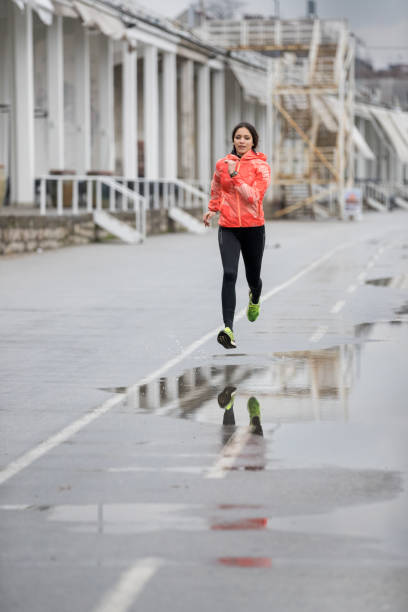 istock Woman jogging through puddles 687437628