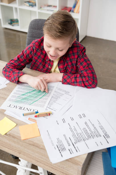 istock Naughty young boy drawing on father's business papers at office 687441054