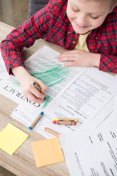 istock Naughty young boy drawing on father's business papers at office 687441606