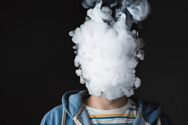 The face of vaping young man The face of vaping young man on black studio background smoking issues photos stock pictures, royalty-free photos & images