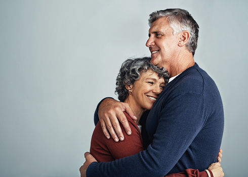 Shot of an affectionate mature couple posing together against a gray background in the studio