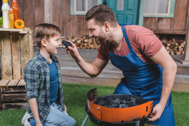 istock side view of smiling father and son preparing grill for barbecue 687442706