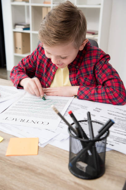 istock Naughty young boy drawing on father's business papers at office 687445364