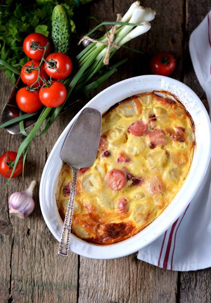 istock Potato casserole with sausages, onions and cheese on an old wooden background. Rustic style. 687445708