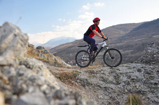 istock Young man riding a bike on hill under a mountain 687449742