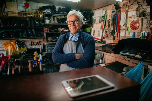 Portrait of a senior man who works as a shoemaker in his cobbler's workshop
