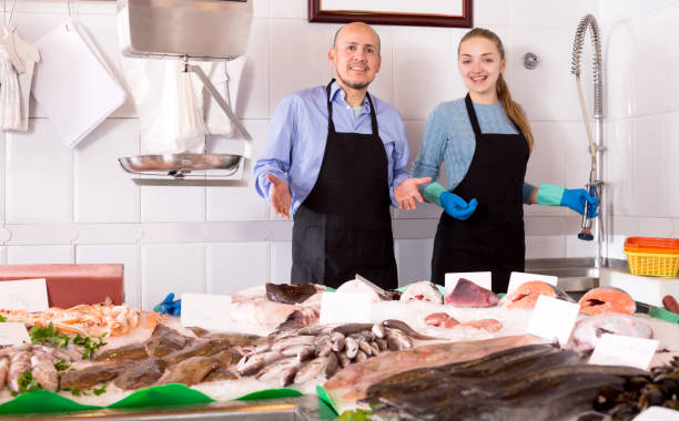 istock Assistant and mature seller offering fresh fish 687471610