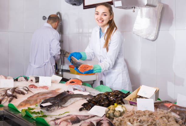 istock seller and young assistant offering fresh fish in shop 687471662