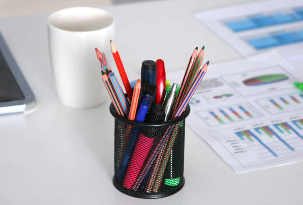 Closeup of white desktop with notepads, pen, coffee cup and other items. Selective focus