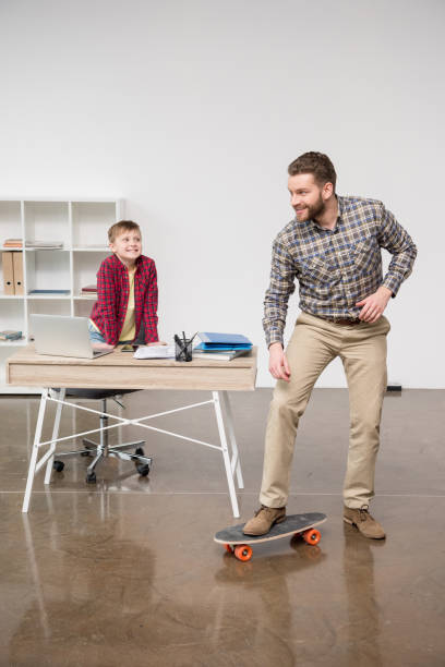 istock Businessman freelancer on skateboard with son at home office 687479498